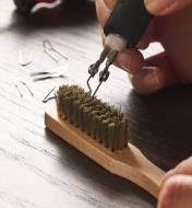 A pyrography tip being cleaned with a brass brush