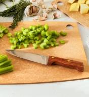 Couteau de chef campagnard exposé sur une planche à découper et entouré de légumes