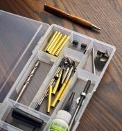 A turned pen placed next to an open divider box containing pen turning kit components