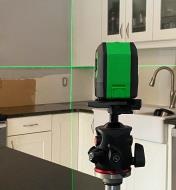 Using a crosshair laser level to align tile edging with the bottom edge of a cabinet