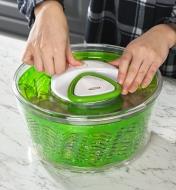 Pushing the brake button on top of a salad spinner