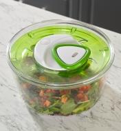 The clear bowl with salad inside and the lid on