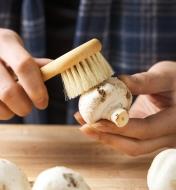 Using a mushroom brush to clean a mushroom