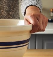 Close-up view of a hand gripping the lip of the Dominion mixing bowl