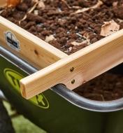 The sifter handle rests on the edge of a wheelbarrow