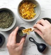 Scooping dried herbs into a tea infuser