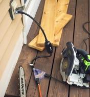 A GFCI cord on a wooden deck with a chainsaw and circular saw plugged into it.