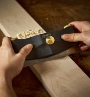 Scraping a wood piece with a scraper held in a  a Veritas scraper holder