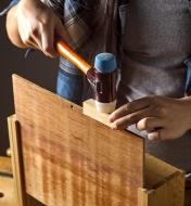 Tapping a wooden panel into place with the white side of a replaceable-face mallet