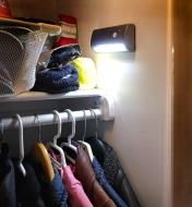 A motion-activated light installed in a closet illuminates clothes and other items