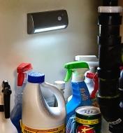 A motion-activated light installed under a sink illuminates assorted cleaning supplies