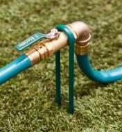 A faucet extension and stand connecting two lengths of hose on a lawn