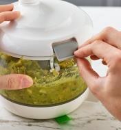 A tab is being locked to securely fasten the lid of a manual food processor