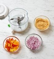 A food processor is next to three bowls showing chopped, minced, and pureed ingredients