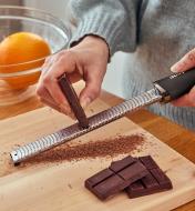 Personne râpant du chocolat à l'aide d'un zesteur en acier inoxydable avec poignée