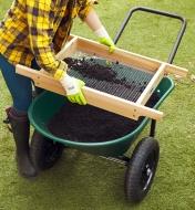 Using a soil sifter over the tub of the wheelbarrow with flat-free tires
