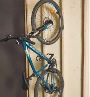 A bicycle suspended vertically against a wall on a bicycle rack