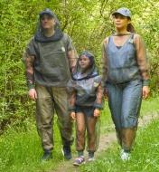 A front view of a woman, a man and a child wearing bug-protection clothing on a hiking trail