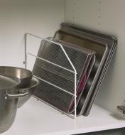 Baking pans leaning against a cabinet wall, supported by a base cabinet divider.