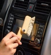 Brushing a car console display using the white bristles of the detail dusting brush