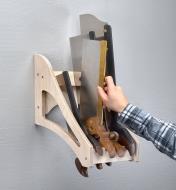 A woodworker selects a tenon saw from among four backsaws stored in a four-saw till