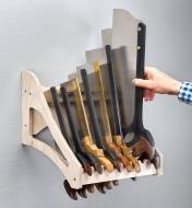 A woodworker selects a tenon saw from among eight backsaws stored in an eight-saw till