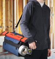 A carpenter’s tool bag hung on a man’s shoulder, holding a tape roll, a tape measure and other tools