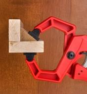 A ratcheting clamp holding a piece of angled trim into a corner