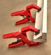 Two ratcheting clamps holding a piece of angled trim into a corner