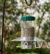 A bird feeder with baffle hanging on a black hook