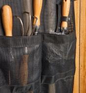 Garden hand-tools are held in mesh pockets.