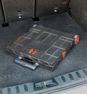 A collapsible cart folded flat and stored in the cargo area of a hatchback car