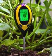 A digital soil meter inserted in soil, showing light, soil temperature and moisture readings