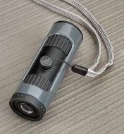 A zoom monocular shown with the included neck lanyard attached