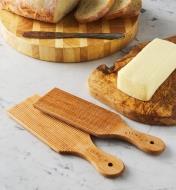 Paire de palettes à beurre sur un comptoir à côté de beurre frais et d'une miche de pain tranchée