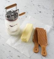 Baratte et palettes à beurre déposées à côté d'une brique de beurre sur une table