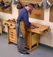 A woodworker marking a live-edge slab on top of a workbench