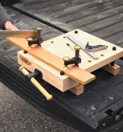 A board clamped down to the workstation being sawed
