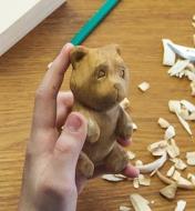 A boy holding a wooden bear he has carved using the bear carving kit