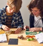 Two young people assemble paper animal models