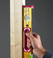 Grasping the handgrip to register the 24" heavy-duty level against a vertical surface