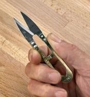 Holding a pair of spring shears between the thumb and forefinger