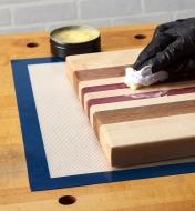 Applying finish to a workpiece positioned on a silicone mat
