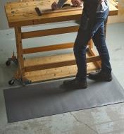 A person standing on a Foam-Cell Anti-Fatigue Bench Mat while planning a board