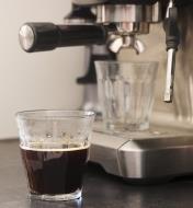An espresso served in a 310ml Duralex Picardie glass, with an espresso maker shown in the background