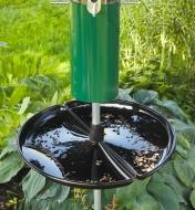 A seed catcher with seeds in it, mounted under a bird feeder.
