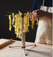 Draping pasta onto the Collapsible Pasta Drying Rack to dry