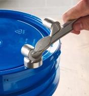 Using the pail opener's built-in hammer to tap the lid back on the pail