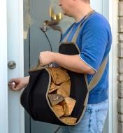 A man carrying firewood in the apron tote opens an entry door