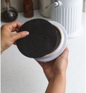 Personne insérant un filtre à charbon actif dans le couvercle d'un seau à compost en porcelaine